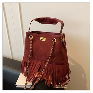 Détail du sac seau bordeaux avec motifs matelassés, franges et bandoulière dorée