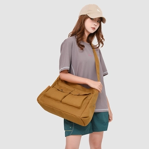 Détail du grand sac bandoulière en toile jaune moutarde avec deux poches avant à boucle