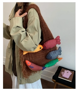 Detail of large brown knit tote bag with colorful plush fish charms for women