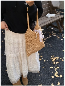 Close-up of handmade woven tote bag with white lace bow and elegant pearl charm detail