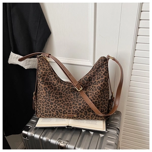 Detail einer Hobo-Tasche mit Leopardenmuster und Lederriemen auf einem Koffer