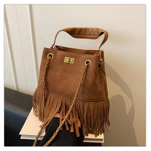 Détail du sac seau en daim marron avec surpiqûres matelassées, franges et chaîne dorée