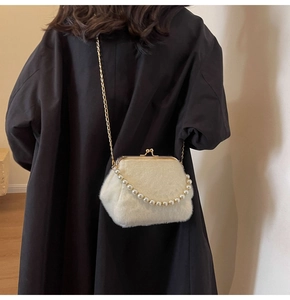 Détail du sac coquillage en peluche blanche avec fermoir doré et chaîne en perles sur manteau