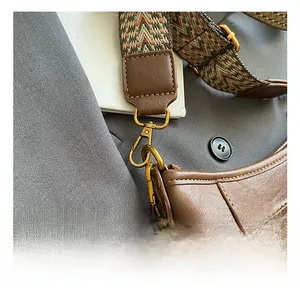 Detail of vintage brown bucket bag showing bronze hook and geometric canvas strap