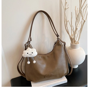 Detail of coffee brown hobo bag with pebble texture and cute white cloud pendant