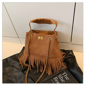 Détail du sac seau en daim marron avec franges et motif de losanges matelassés