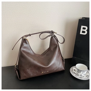 Detailansicht der dunkelbraunen Hobo-Tasche aus glänzendem Leder mit Goldreißverschluss