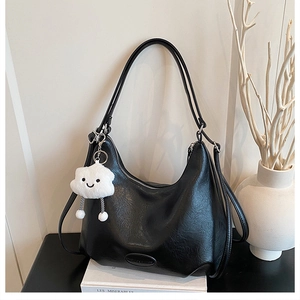 Detail of black hobo bag with pleated texture and a cute white cloud plush pendant