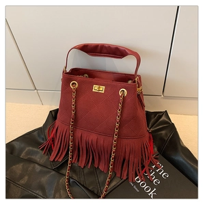 Détail macro du sac seau bordeaux matelassé avec de longues franges et un fermoir doré