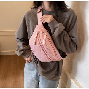Détail du sac de poitrine matelassé rose avec texture cœur et tirettes tissées