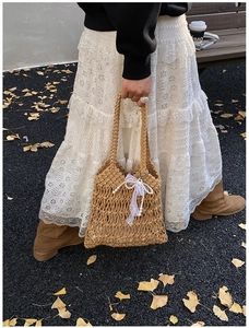 Detail of hand-woven crochet tote bag featuring white lace bow and pearl charm accents