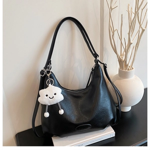 Detail of black leather shoulder bag with fine texture and cute cloud plush charm