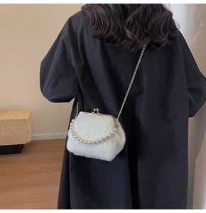 Détail du sac en peluche blanc avec poignée en perles et chaîne sur manteau noir