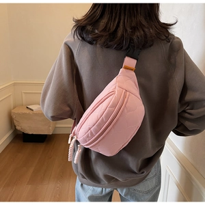Gros plan sur un sac banane rose matelassé avec motifs de cœur et bandoulière réglable