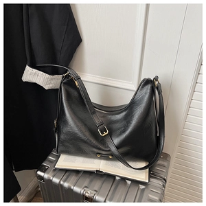 Detail einer schwarzen Vintage Hobo-Tasche aus Leder mit goldener Schnalle auf Koffer