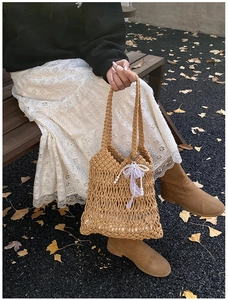 Detail of hand-woven hollow tote bag with pearl lace bow and inner pouch in autumn setting