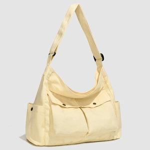 Détail du sac cabas en toile beige avec plusieurs poches fonctionnelles et rabat frontal