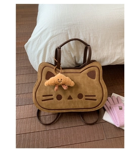 Detail of a brown cat-shaped faux suede backpack with embroidery and croissant charm
