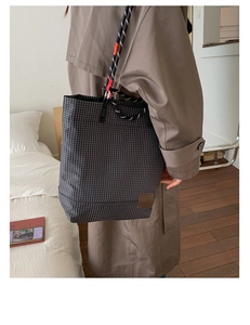 Dettaglio della borsa tote a scacchi con spalline in corda intrecciata e logo in pelle