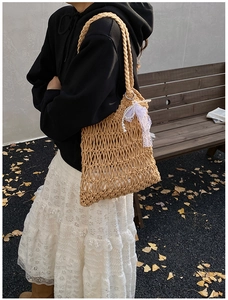 Detail of woven beach tote with pearls, lace bow, and autumn ginkgo leaf backdrop
