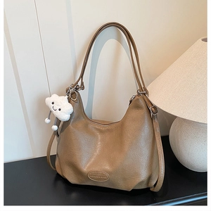 Macro detail of brown retro faux leather bag with cloud charm and brand embossing