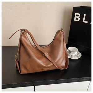 Detailansicht der braunen Hobo-Tasche mit Fokus auf Ledertextur und goldene Metallbeschläge