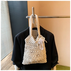 Detail of off-white hand-woven tote bag with twisted handles and delicate lace bow accent