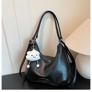 Detail of black crescent shoulder bag in PU leather with cute white cloud plush pendant