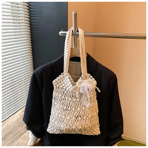 Detail of white crochet tote bag featuring mesh knit, lace bow, and pearl accents
