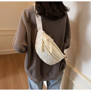 Détail du sac à bandoulière matelassé crème avec motif cœur sur le dos du mannequin