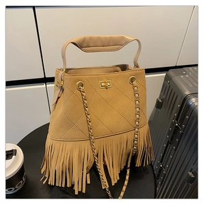 Détail du sac seau vintage en daim camel avec franges et fermoir rotatif doré élégant