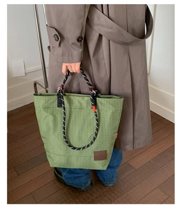 Dettaglio della borsa tote a quadri verdi con manici in corda intrecciata e inserto in pelle