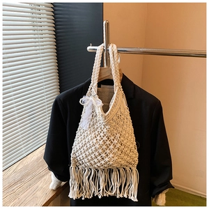 Detail of cream macrame tote bag featuring long tassels and pearl lace bow ornament