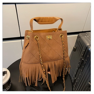 Vue détaillée du sac seau en daim marron avec de longues franges et une bandoulière dorée