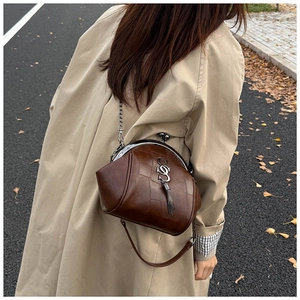 Detail einer braunen Vintage-Umhängetasche aus Leder mit Logo und Metallfransen-Akzent