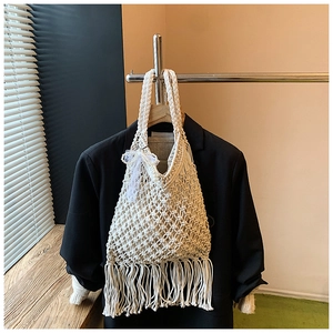 Detail view of handmade woven tote bag with fringe tassels and white lace bow