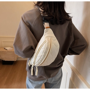 Détail du sac bandoulière matelassé blanc cassé porté par un mannequin, style minimaliste