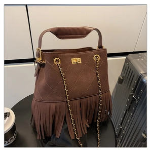 Détail du sac seau en daim marron foncé avec motifs matelassés et longues franges