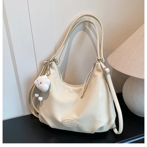 Detail of beige faux leather tote with plush cloud charm and adjustable shoulder strap