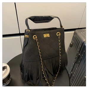 Détail du sac seau matelassé noir avec de longues franges et un fermoir doré luxueux