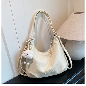 Detailed macro of cream faux leather tote bag with cloud charm in home setting
