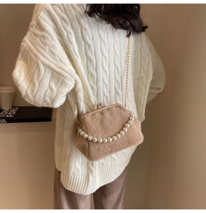 Détail du sac coquillage en peluche avec poignée en perles sur une tenue de mannequin