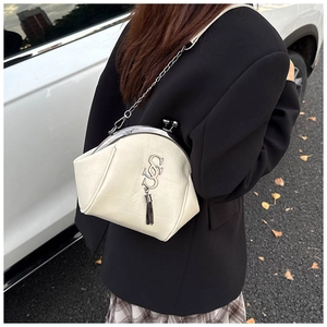 Detail der cremefarbenen Crossbody-Tasche mit Retro-Metallverschluss und Quastenanhänger