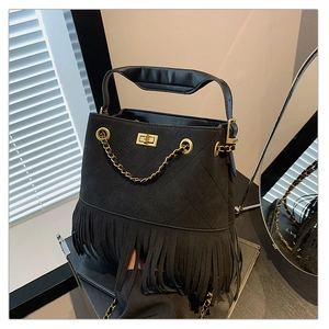 Détail du sac seau noir en daim matelassé avec fermoir doré et longues franges de style bohème