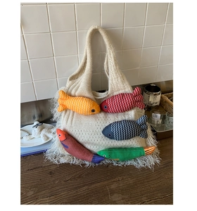 Detail of off-white knitted tote bag featuring colorful 3D fish charms and tassel fringe