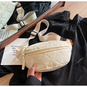 Détail du sac de poitrine matelassé blanc cassé avec bandoulière réglable et étiquette