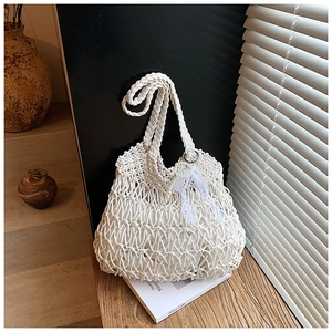 Detail der weißen Makramee-Tasche mit Spitzenschleife und strukturierter Baumwollwebung
