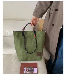 Dettaglio della borsa tote a quadri verdi con manici in corda e toppa logo in pelle