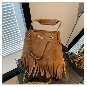 Détail de sac seau en daim marron avec franges et fermoir rotatif en métal doré