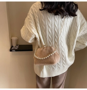 Détail du sac coquillage en peluche avec poignée en perles et chaîne sur un mannequin